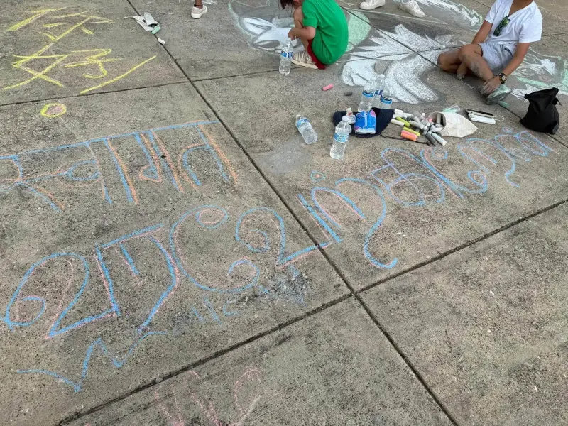Chalk writing in Hindi and Telugu script filling two slabs of the walkway, water bottles and chalk boxes at the edge