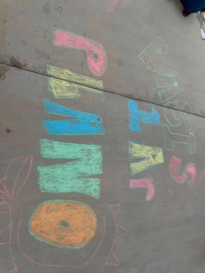 “BASIS PLANO” written out in big blocky chalk letters, pink, yellow, blue and green, with a doughnut drawn below
