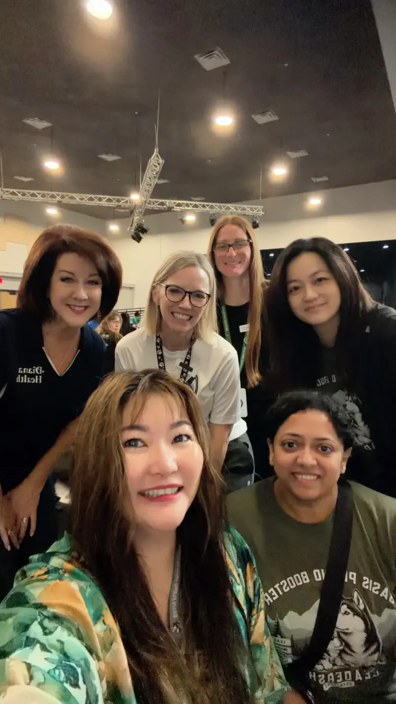 A selfie of Booster volunteers and staff with the Diana Health representative in the cafeteria