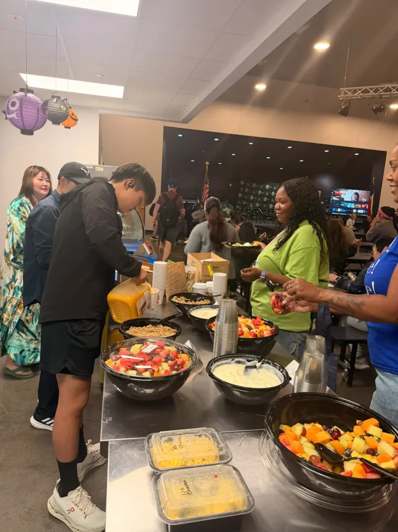Teachers and staff chatting as they help themselves to fruit salad, granola, yoghurt and orange juice