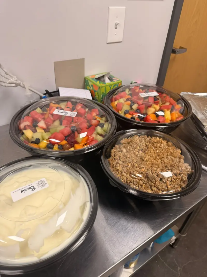 Covered bowls of fruit salad, granola and yoghurt waiting on the counter before the breakfast opened
