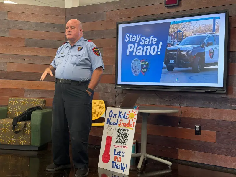 Plano PD Public Safety Officer Kevin speaking to families beside a “Stay Safe Plano!” slide, the Booster’s “Our Kids Need Shade!” fundraising thermometer propped in front