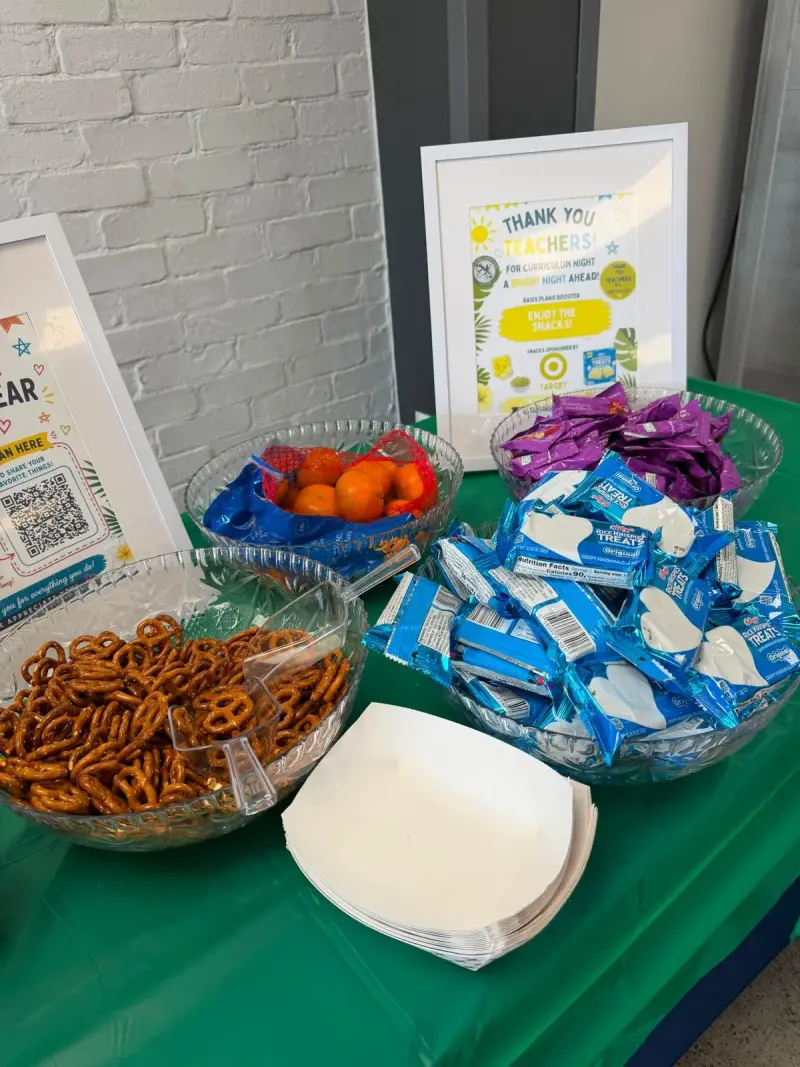 Glass bowls of pretzels, clementines, fruit snacks and Rice Krispies Treats on the teacher snack table, with the Target thank-you sign behind