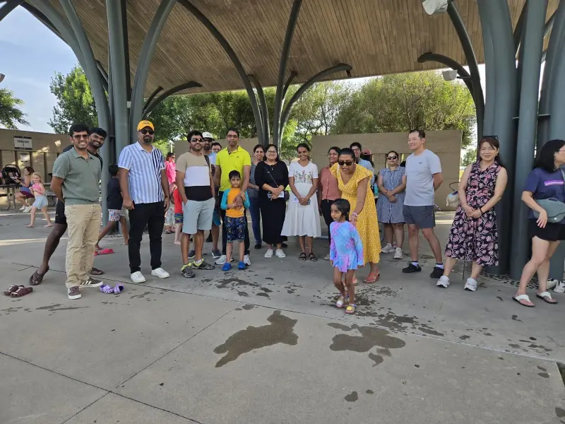 The whole meetup gathered under the park pavilion for a group photo, a small child running out in front